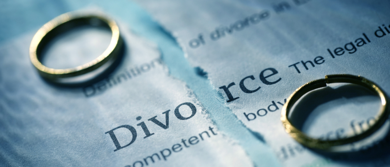 Two rings on top of a torn divorce contract symbolizing divorce
